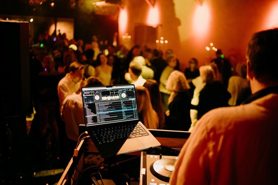 DJ Pult auf einer Bühne vor tanzenden Menschen
