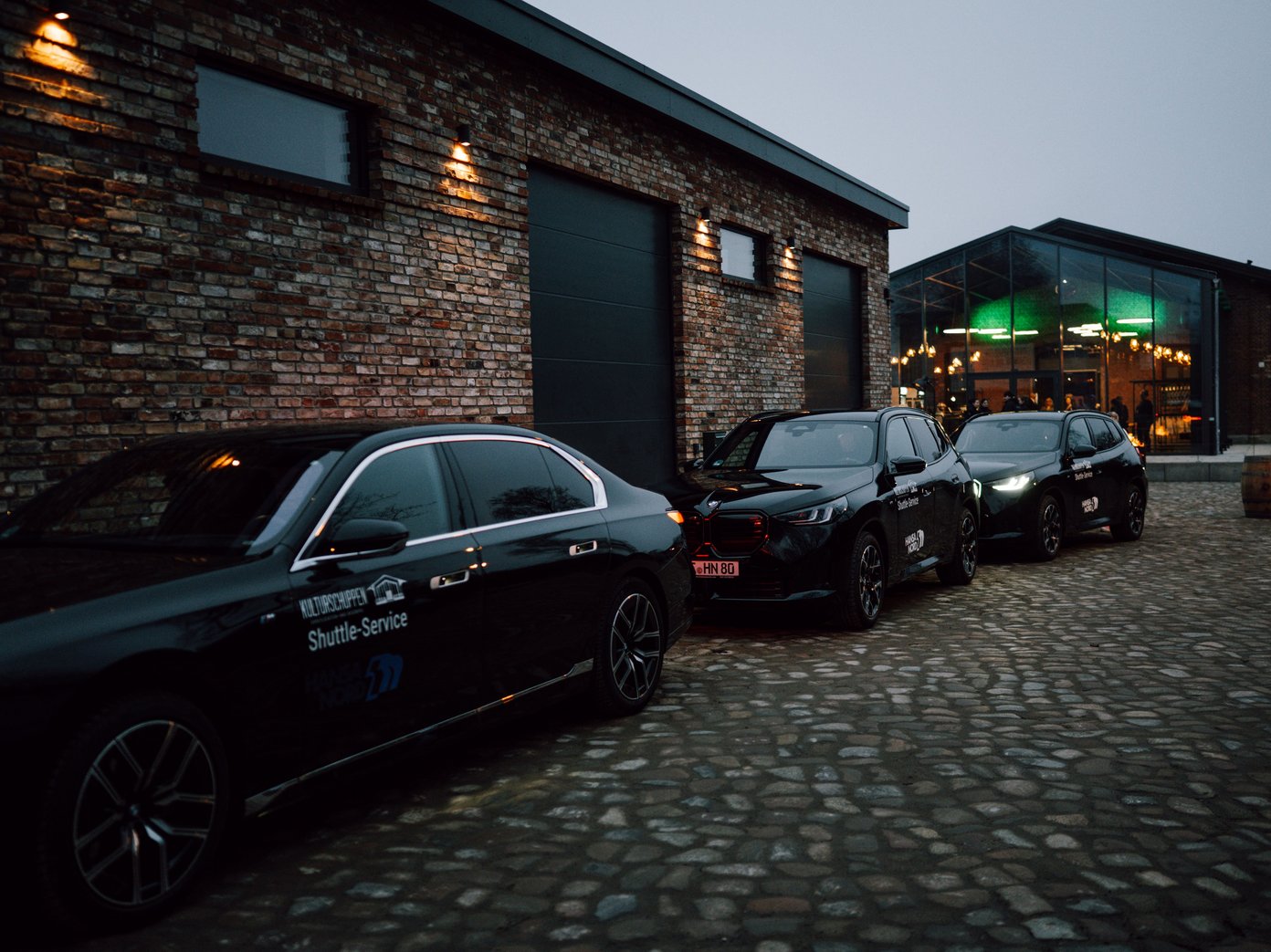 Shuttle Service Drei BMW Autos vor den Gleisgaragen mit Ansicht vom Kulturschuppen