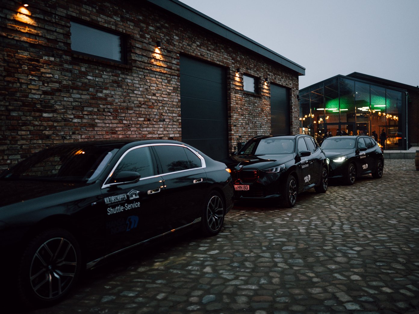 Shuttle Service Drei BMW Autos vor den Gleisgaragen mit Ansicht vom Kulturschuppen