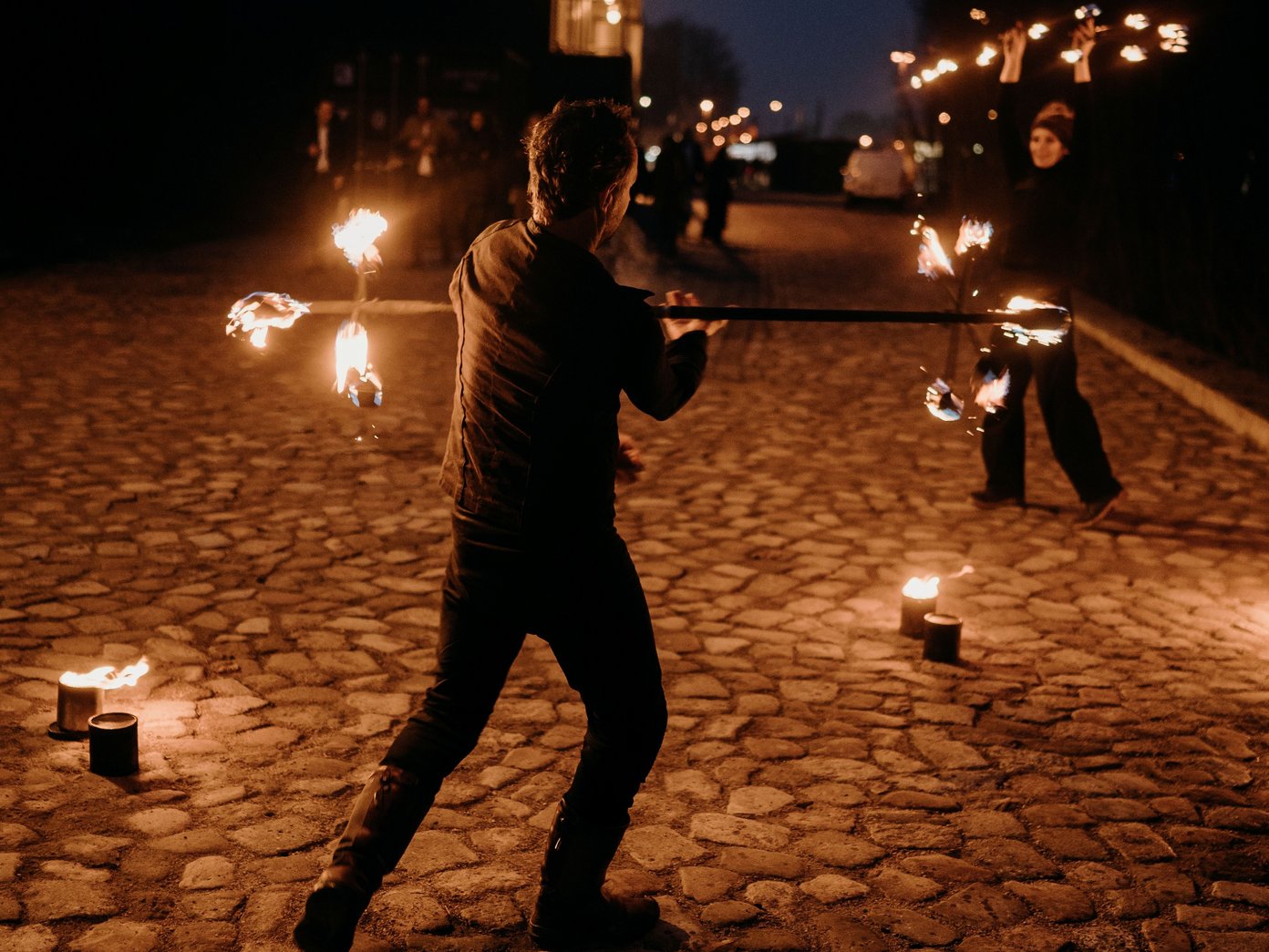 Feuerkunst Zwei Personen machen Kunst mit Feuer auf Kopfsteinpflaster