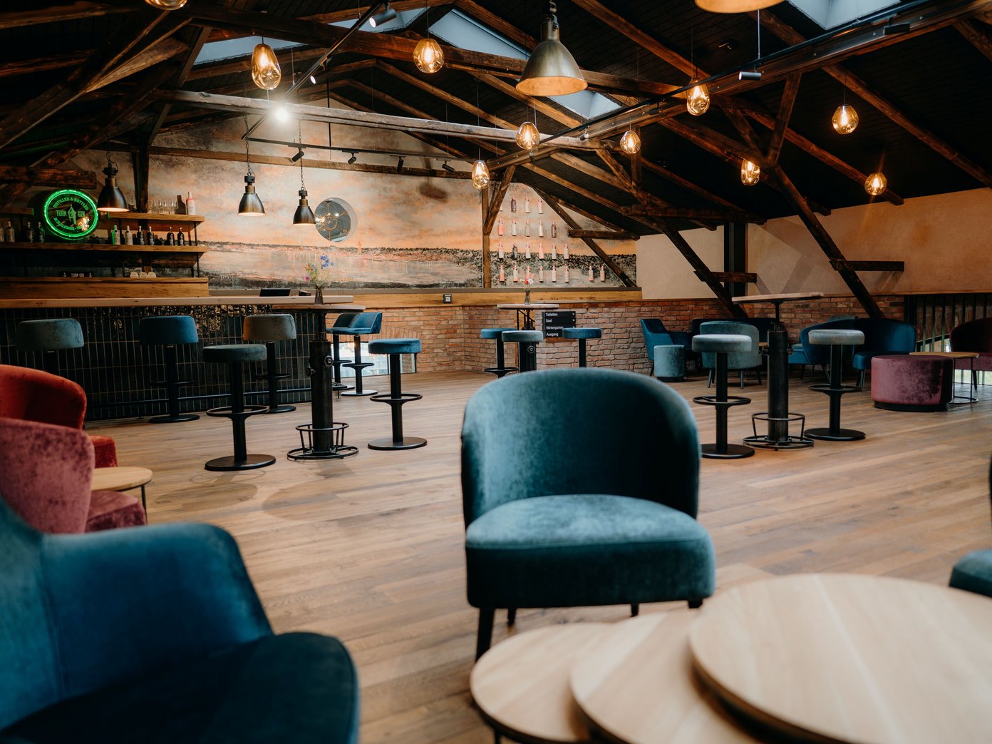 Empore aufgeräumt Gemütliche Sessel und Bartische sowie eine Bar im Hintergrund