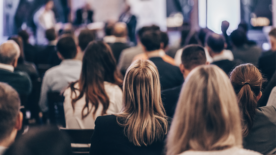 Tagungen Hinterköpfe von sitzenden Menschen die auf eine Bühne schauen