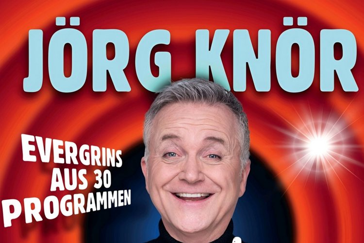 Roter Hintergrund, Jörg Knör mit Tourtitel "Simply my Best" in der Hand